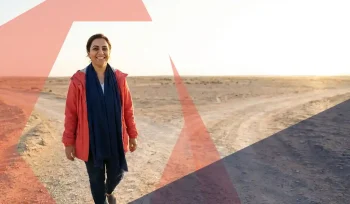 Zelfverzekerde vrouw van Midden-Oosterse afkomst op een kruispunt, stapt vooruit in een licht landschap met geometrische vormen en gouden zijlicht.