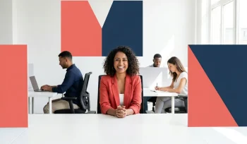 Zuid-Aziatische vrouw werkt zelfverzekerd aan een modern bureau in een lichte, open werkruimte met diverse collega's.